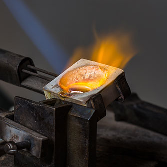 Molten gold in a crucible with a flame